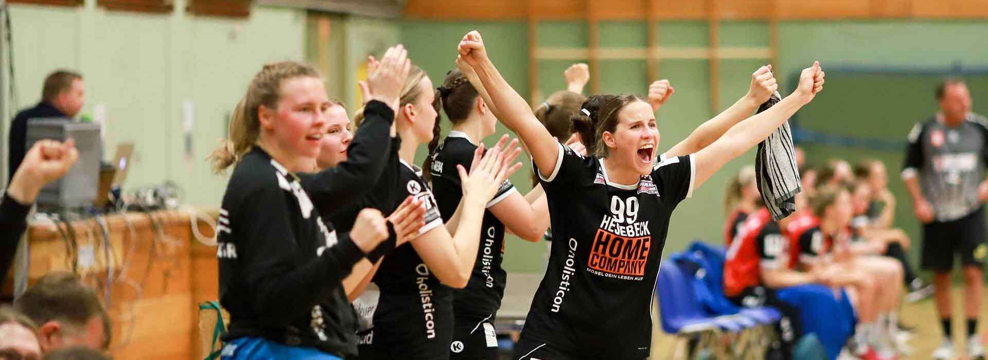 Jubelnde Handballspielerinnen an der Seitenlinie, die ihre Unterstützung für ihr Team zeigen.